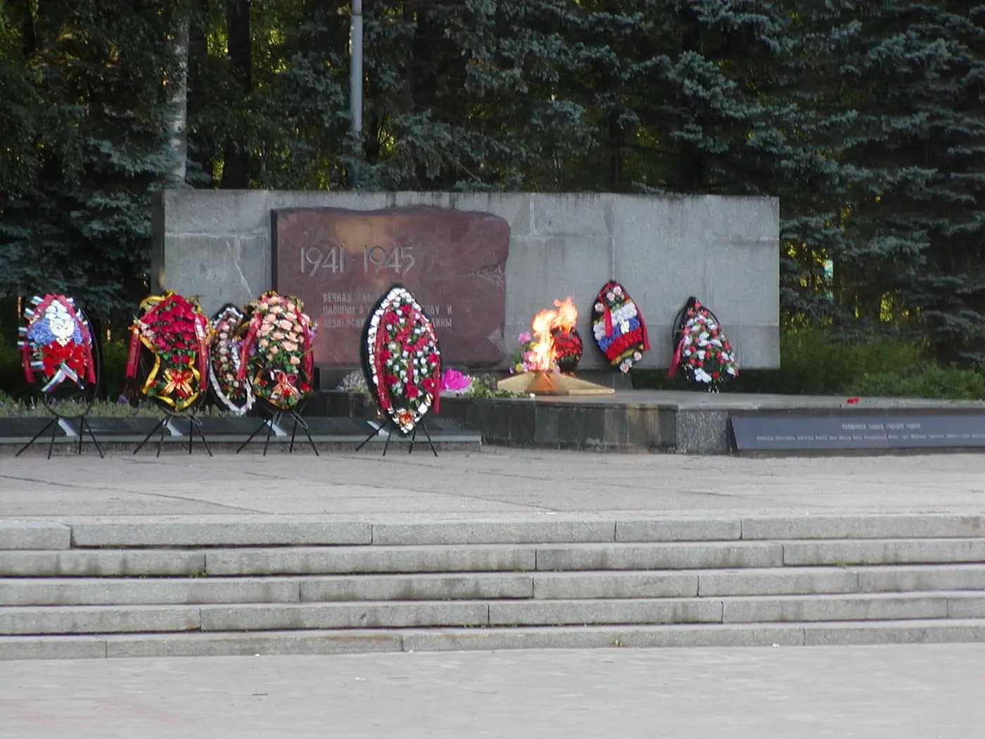 Вечный огонь и венки у мемориальной стены